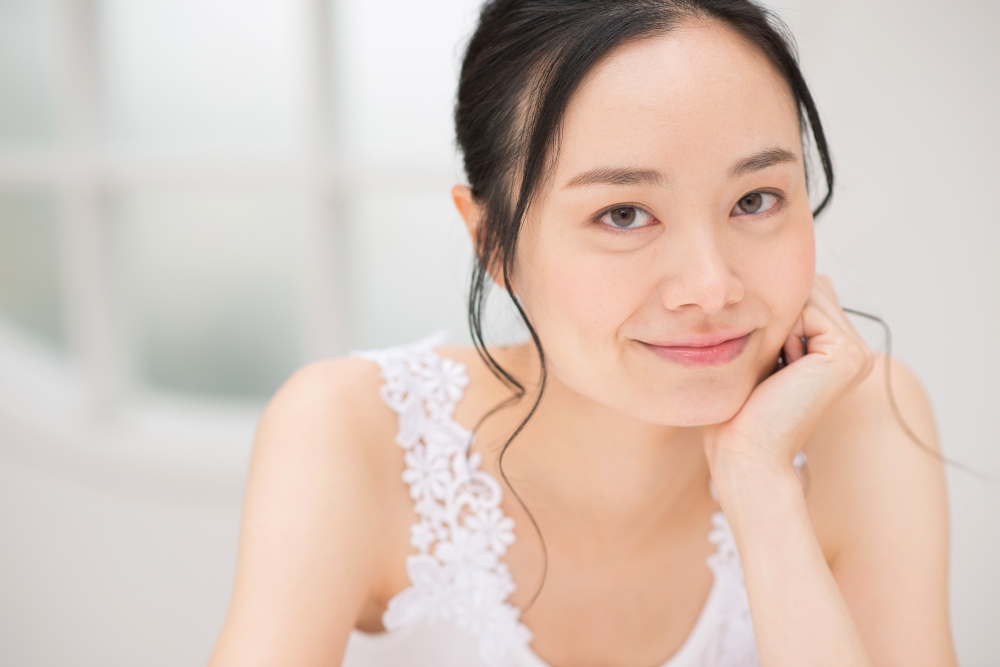 頬に手を添えて笑顔を見せる若い女性